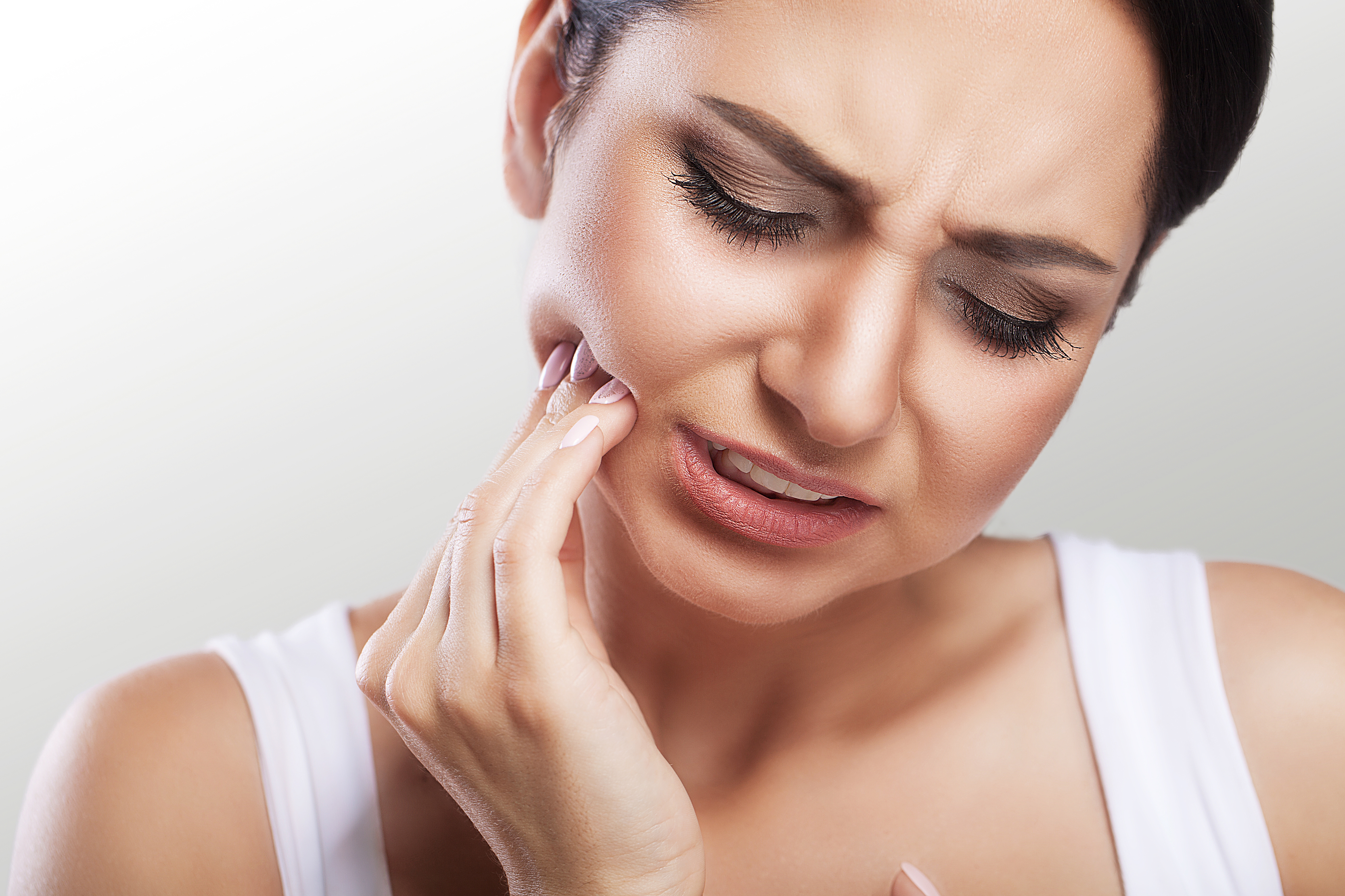 woman holding cheek tooth sensitivity dental pain emergency dentist sore mouth teeth
